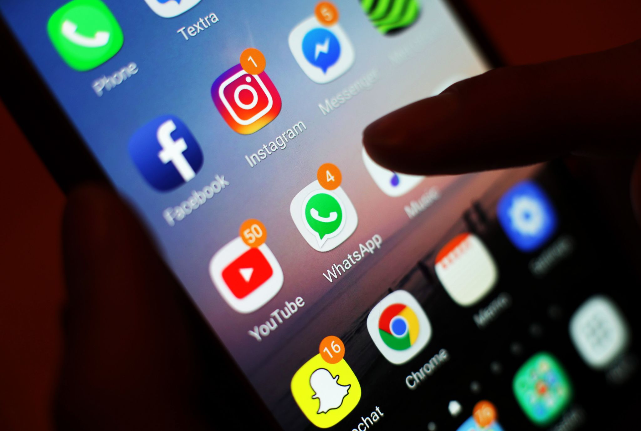 Ein Smartphone-Display mit Symbolen von Apps, die man auch zum Telefonieren und Videotelefonieren nutzen kann, etwa Facebook Messenger und Whatsapp.