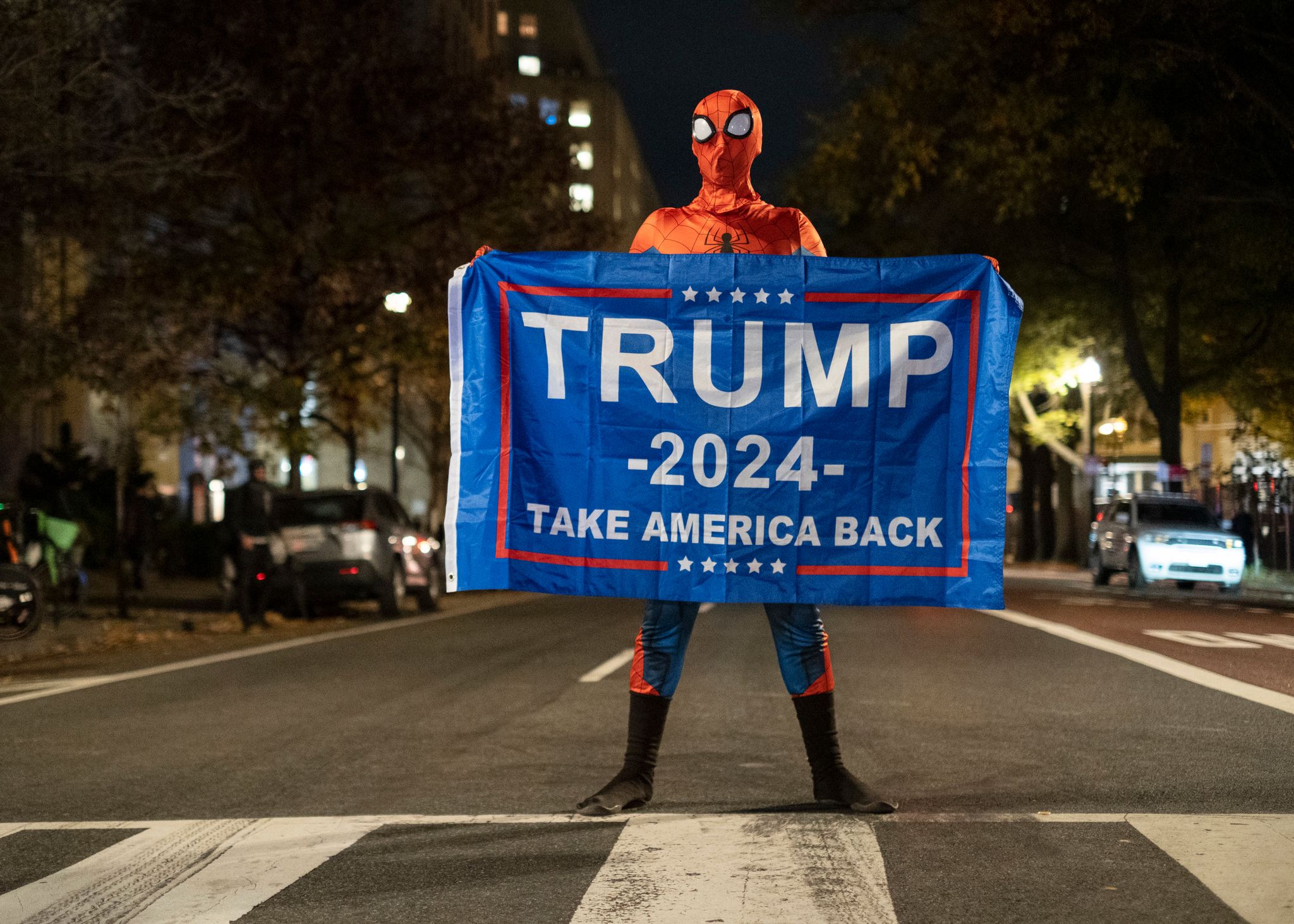 Trump-Unterstützer im Spider-Man-Kostüm mit einem Trump-Transparent am Tag der US-Präsidentschaftswahl 2024 in Washington.