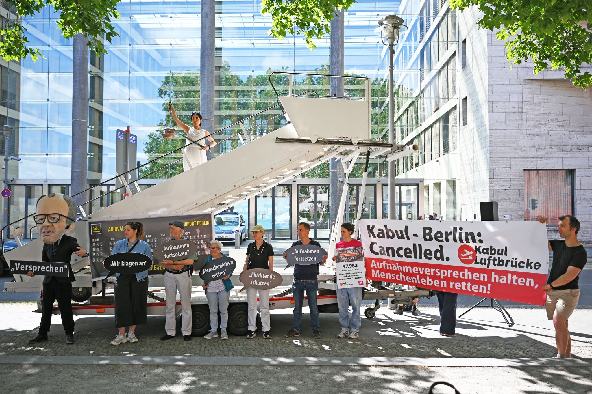 Aktivsten stehen während einer symbolischen Protestaktion am Weltflüchtlingstag zur Unterstützung mehrerer Klagen von Afghanen gegen die Bundesregierung vor dem Auswärtigen Amt.