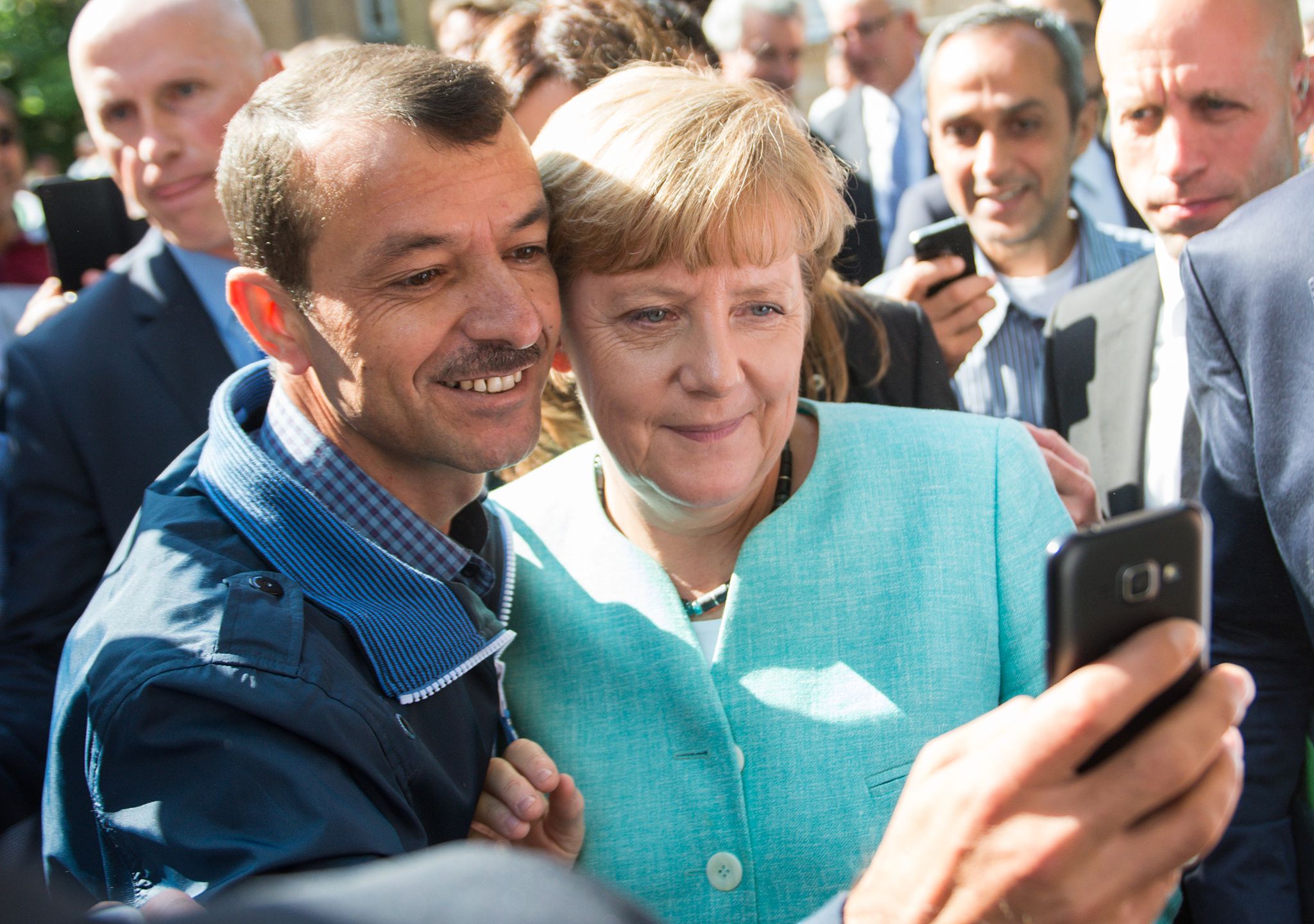 Bald zehn Jahre her: Angela Merkel (CDU) lässt sich nach dem Besuch einer Erstaufnahmeeinrichtung für Asylbewerber in Berlin-Spandau für ein Selfie zusammen mit einem Flüchtling fotografieren. (Archivbild)