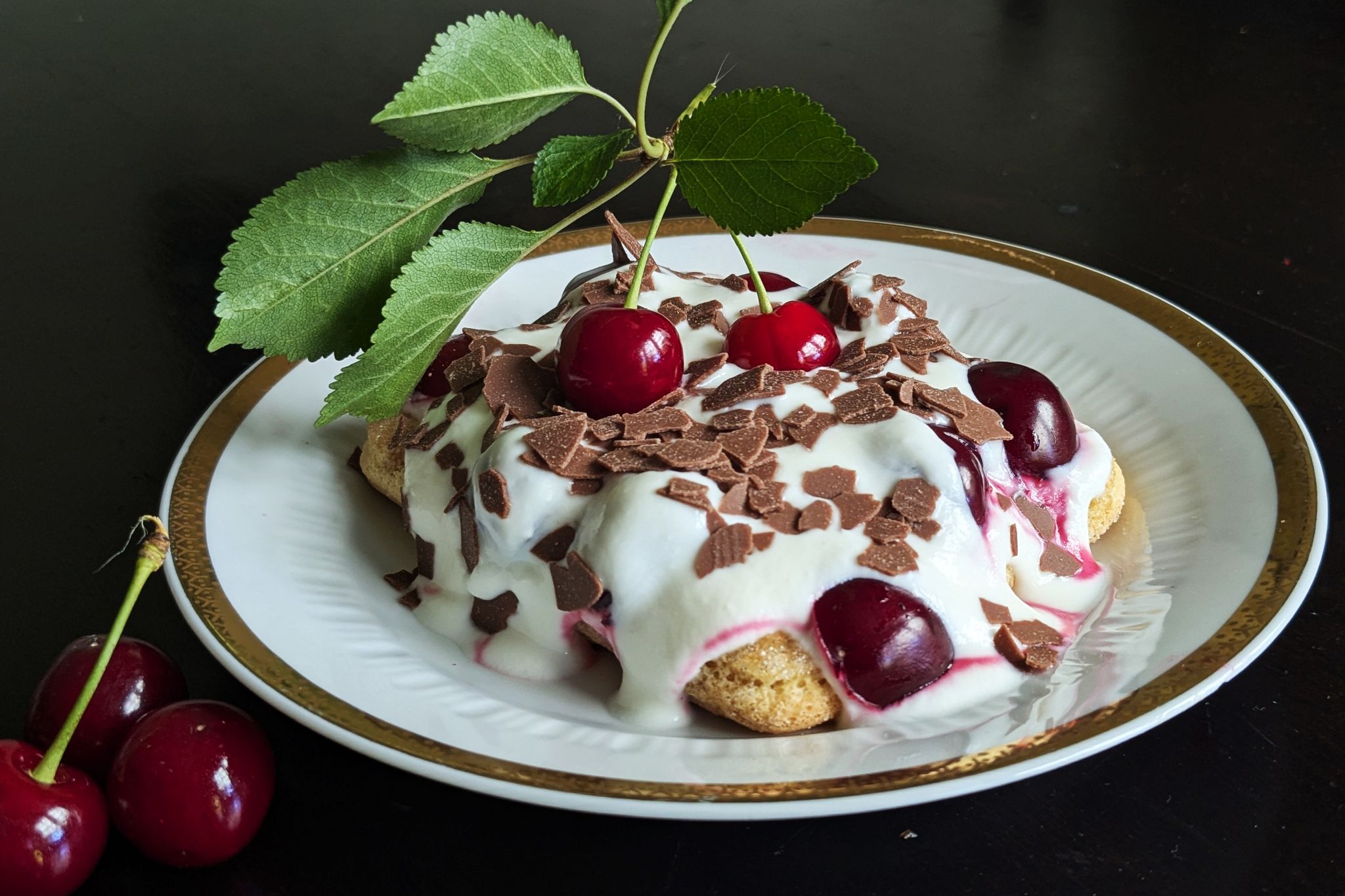 Auf die mit Espresso getränkten Löffelbiskuits kommen eine Quark-Sahne-Masse und reichlich Kirschen. Das Tiramisu wird mit Schokoraspeln getoppt.