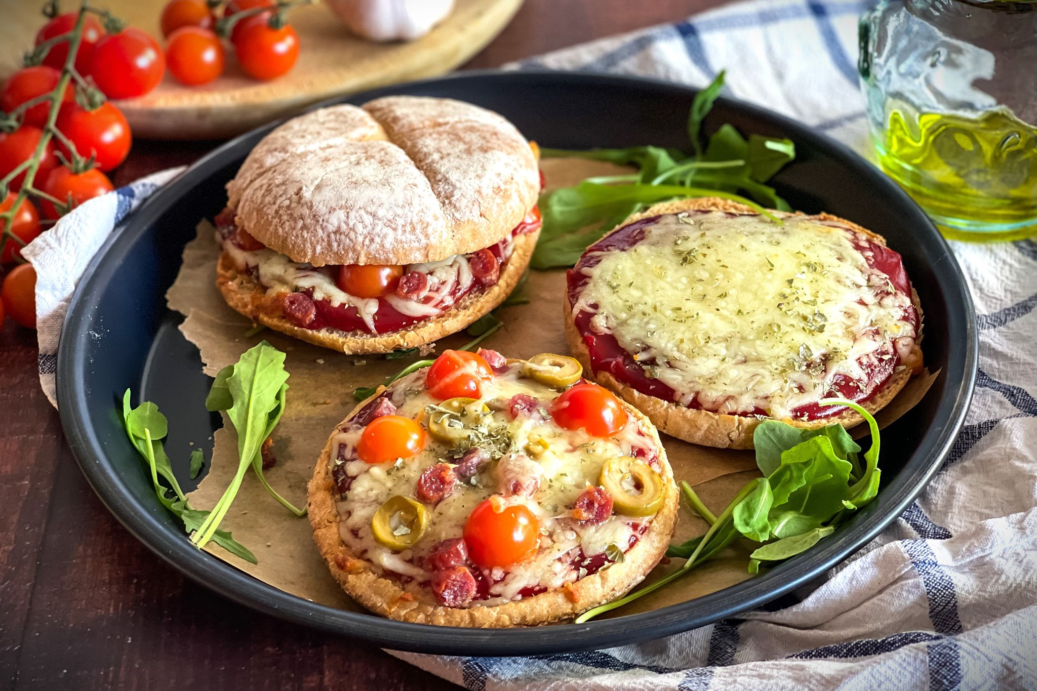 Ein rustikales Hamburgerbrötchen wird zur Pizzabasis, belegt mit Tomatenketchup, geschmolzenem Mozzarella und mediterranen Zutaten.