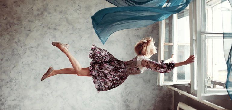 Foto: JulPo/iStock Frau vor Fenster, windig, hält sich am Fenster fest