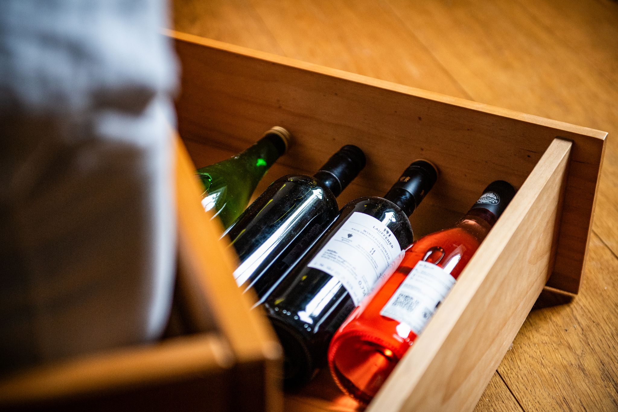 Da liegen sie gut: Weinflaschen lagern in einem Bettkasten im Schlafzimmer - ohne große Temperaturschwankungen.