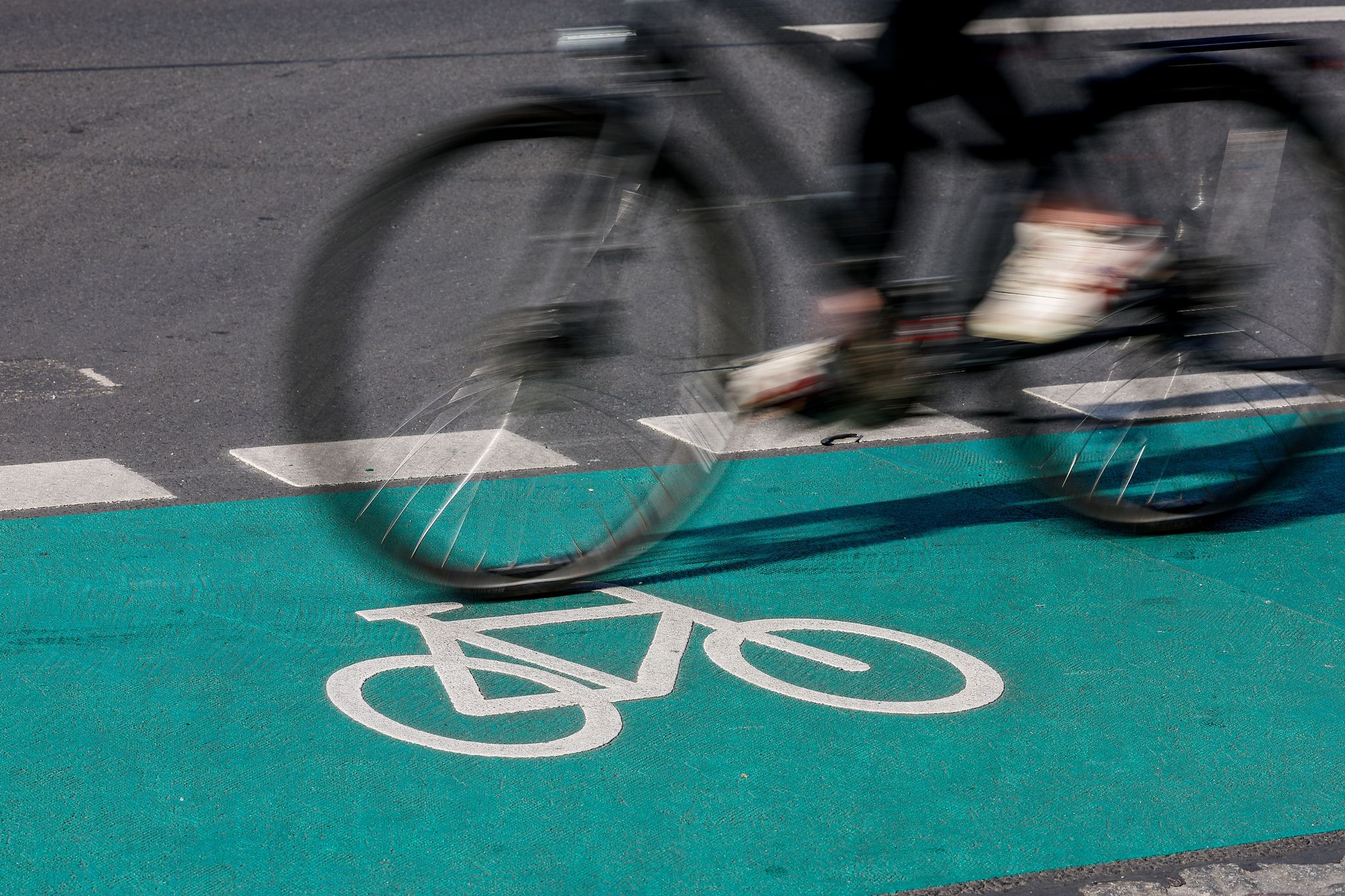 Eine Radfahrerin fährt in Leipzig über einen grün eingefärbten Radweg.