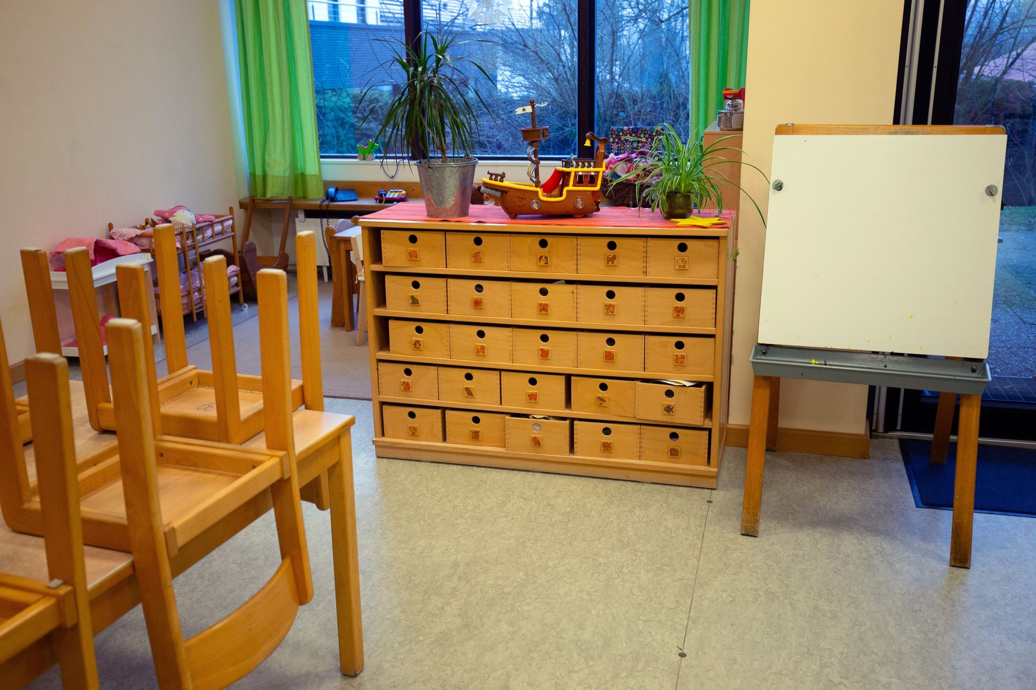 Blick in den Raum einer Kindertagesstätte mit hochgestellten Stühlen.